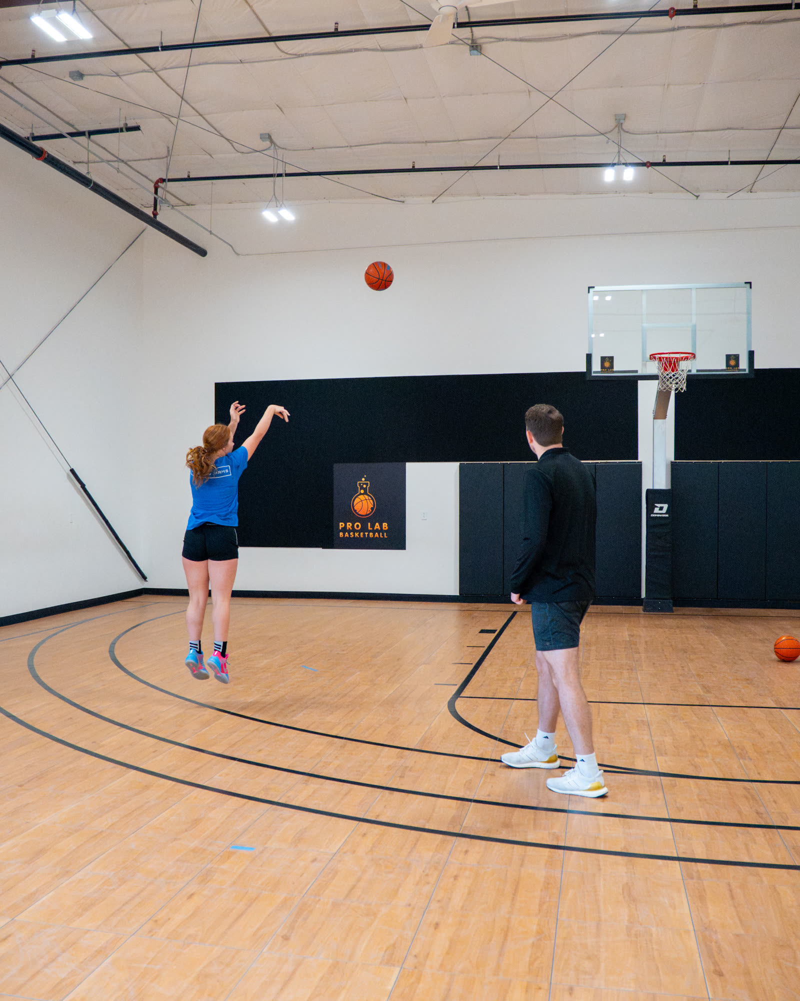 Athlete shooting while a coach rebounds in a private session